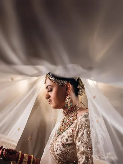 An artistic shot of the bride under her veil, with light creating beautiful rays around her. This technique adds a magical and ethereal quality to the portrait.