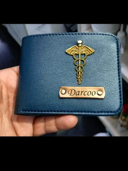 A close-up of a blue leather wallet customized for 'Darcoo' with a caduceus charm, perfect for a medical professional.