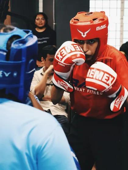 A young fighter stays focused and defensive during a competitive match.