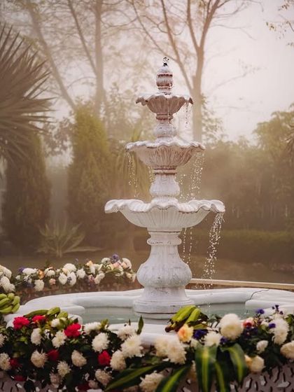 A serene white fountain surrounded by flowers, a beautiful and tranquil feature at the South Indian wedding venue.