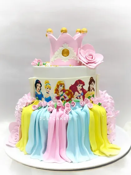 A grand three-tier Disney princess cake featuring beautiful draping in pastel colors. Topped with a crown, it's a cake fit for royalty.
