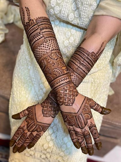 A classic crossed-arms pose to showcase the full beauty of this bridal mehendi. The design features bands of different patterns for a rich look.