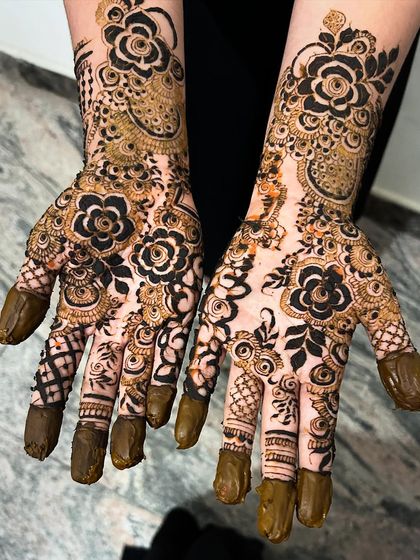 A stunningly detailed bridal design with bold, black-filled flowers that create a powerful contrast. The fingertips are fully covered, a classic element of traditional bridal mehendi.