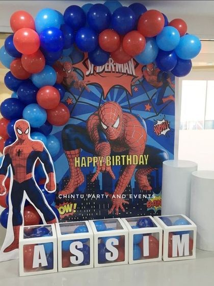 A dynamic Spiderman themed decoration with a large character cutout and personalized letter boxes. The red and blue balloon arch frames the action-packed backdrop perfectly.