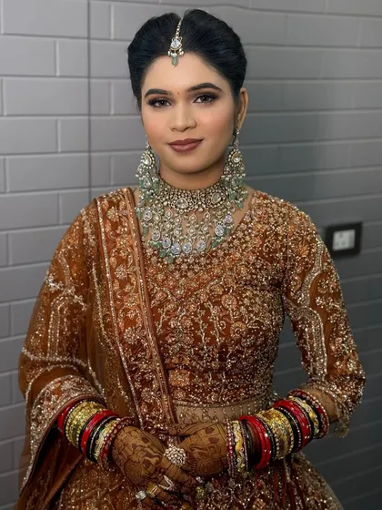 A bride in a beautiful bronze-colored lehenga, with a statement diamond necklace.