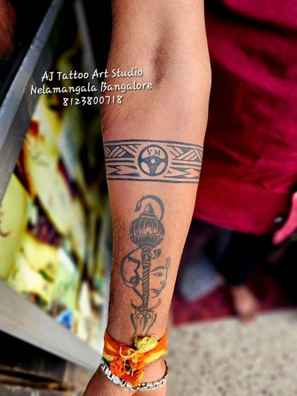 A unique armband tattoo that incorporates a steering wheel symbol along with a depiction of Hanuman's mace.