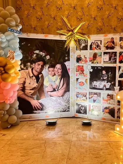 A heartwarming photo collage backdrop for a first birthday, surrounded by a beautiful balloon arrangement and a light-up number '1'.