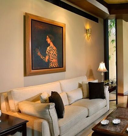 A simple and elegant living room setup. A comfortable off-white sofa is complemented by dark wood furniture and soft lamp lighting, creating a timeless and inviting space.