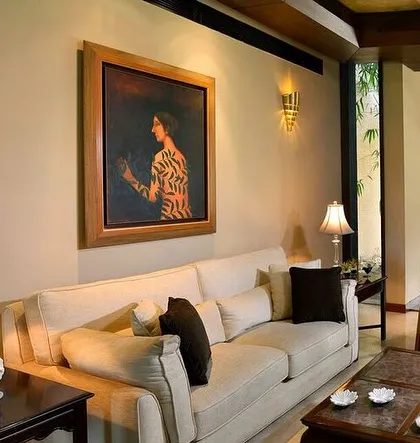 A simple and elegant living room setup. A comfortable off-white sofa is complemented by dark wood furniture and soft lamp lighting, creating a timeless and inviting space.