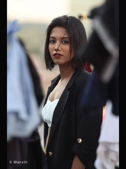 A candid, over-the-shoulder shot of a model with a sharp bob haircut. The look, featuring a white top and black blazer, is effortlessly chic and modern.