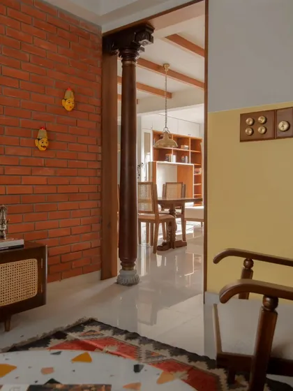 This image captures the layered view from the living area through the dining space. The traditional wooden column serves as a beautiful structural and aesthetic element, grounding the design.