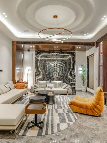 A wide view of a contemporary living room, showcasing a mix of furniture, a statement marble wall, and custom wooden cabinetry for the entertainment unit.
