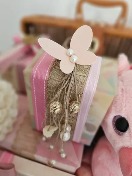 Another detail from the pink trunk hamper. This small gift is adorned with a paper butterfly and delicate pearl and gold bead tassels, adding a touch of whimsy.