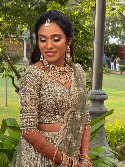 An outdoor portrait of Haritha. The natural light beautifully highlights her flawless makeup and the intricate details of her lehenga.
