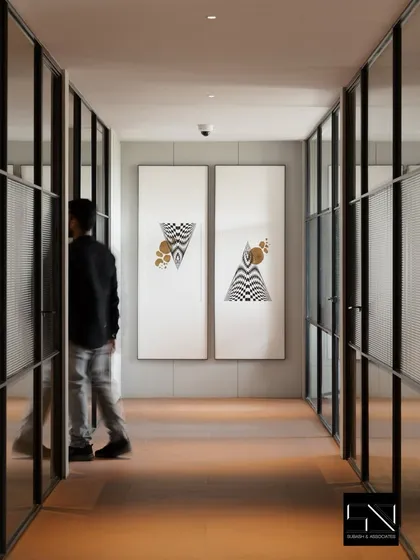 A corridor at Jubilee Headquarters defined by fluted glass walls and minimalist black frames. This design choice allows light to travel through the space while maintaining privacy, with large-scale geometric art adding a point of visual interest.