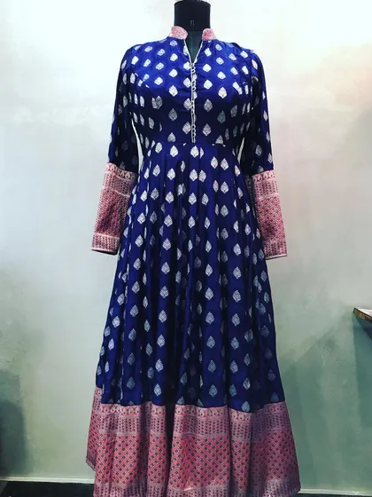 A grand Anarkali stitched from a royal blue brocade saree. The design includes a high neck and uses the saree's pallu for the contrasting cuffs.