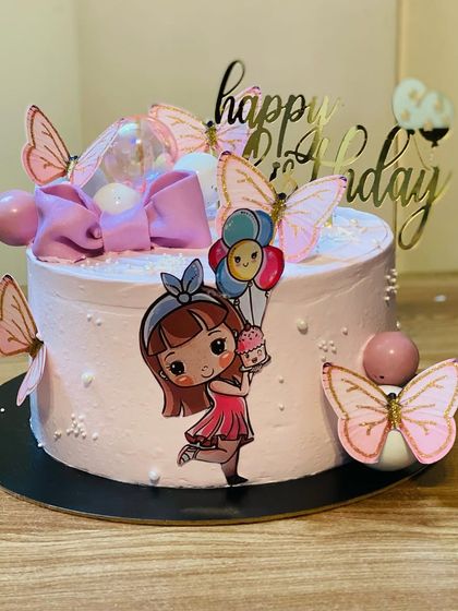 A sweet pink birthday cake with a cute girl and butterfly decorations.
