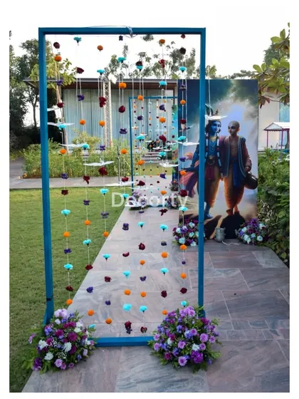 A decorative entrance element with hanging flower garlands, leading guests toward a large painted backdrop.