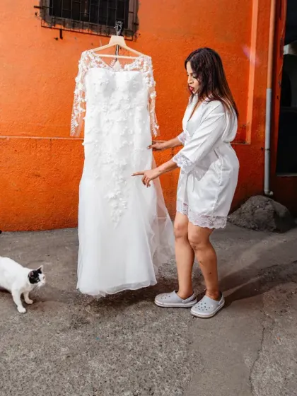 "No messing with my dress." The bride and a friendly cat stand guard over the wedding gown.