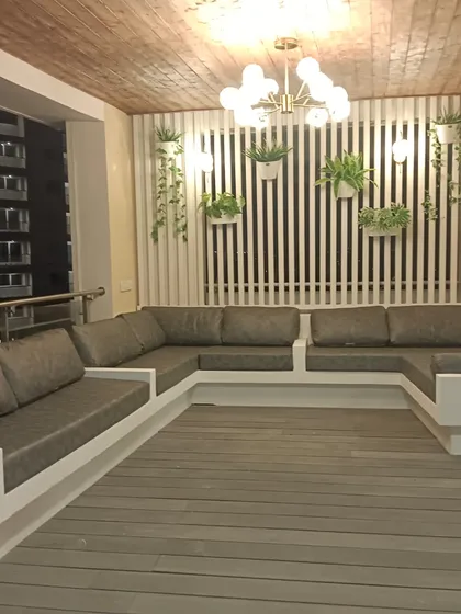 Imagine hosting friends and family in this spacious balcony lounge. We designed and built this expansive U-shaped seating, installed a modern slatted feature wall, and added a beautiful wood-paneled ceiling with a statement chandelier.