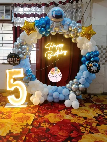 An astronaut-themed 5th birthday with a circular balloon frame, neon sign, and a large marquee number '5'.
