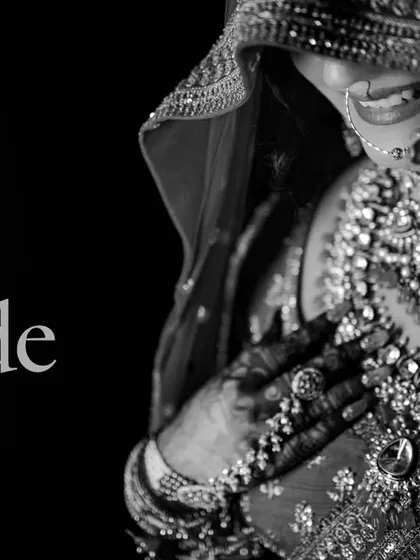 A classic black and white shot that captures the bride's joyful smile. This timeless style emphasizes the emotion and the intricate details of her jewelry and henna.