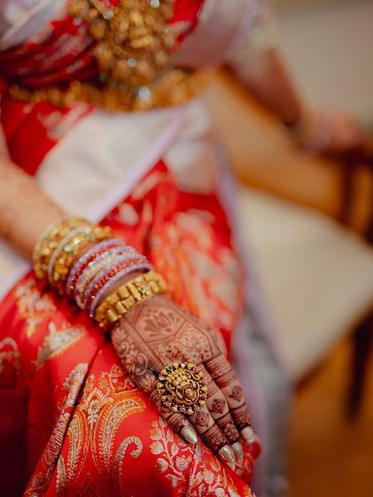 Another detail shot of the hand, capturing the texture of the saree, the gold jewelry, and the intricate henna patterns.