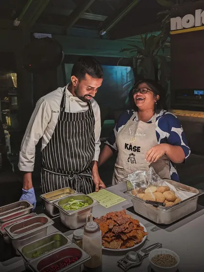 A moment of shared laughter between Chef Goku and cheesemaker Namrata Sundaresan during their 'Käse' pop-up. This collaboration brought the unique flavors of Chennai-inspired cheese to our Bangalore glasshouse.
