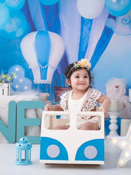 A dreamy first birthday shoot with a hot air balloon theme. The soft blue and white color palette creates a serene and magical atmosphere.