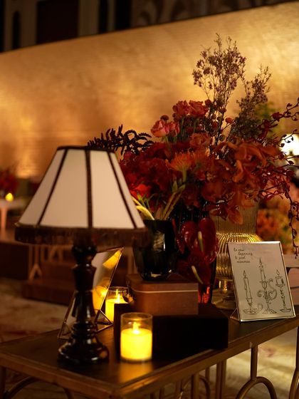 A vintage-style table lamp and floral arrangement, part of the curated decor for the speakeasy theme.