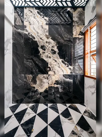 A bold bathroom design from our Hennur residence. Here, we used CNC-cut Nexion tiles to create a dramatic geometric floor pattern that contrasts with the fluid, natural veins of the black and white marble walls, turning a functional space into a work of art.
