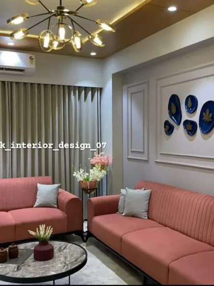 A living room with soft pink sofas and elegant wall paneling. The modern chandelier and marble-top coffee table complete this chic and comfortable space.