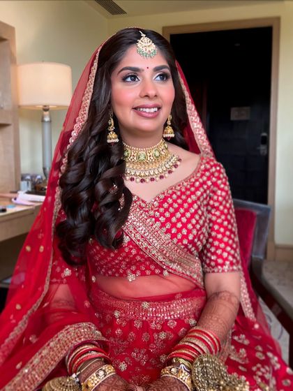 Looking out with anticipation. The side profile highlights the soft hairstyle and the flawless finish of her makeup.