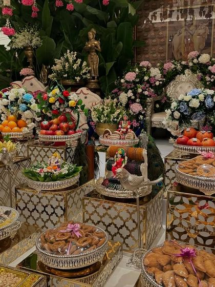 A vibrant offering table with colorful flower arrangements and a variety of traditional sweets and fruits.