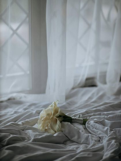 The bridal bouquet resting on the bed, a symbol of love and new beginnings. This soft, romantic shot captures the calm before the wedding festivities.