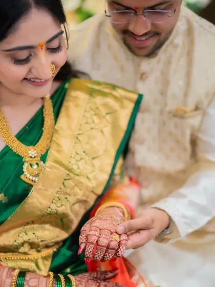 A close-up detail shot of the groom admiring the intricate mehendi on the bride's hand. It’s these small, tender moments that tell a powerful story.