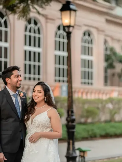 A candid moment of laughter outside a beautiful building after a white wedding. This shot captures the relaxed happiness and love between the newlyweds.