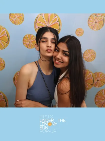 Friends posing at the PTAT pop-up with its fun lemon-themed backdrop. We can work with any custom backdrop to match the theme of your event.