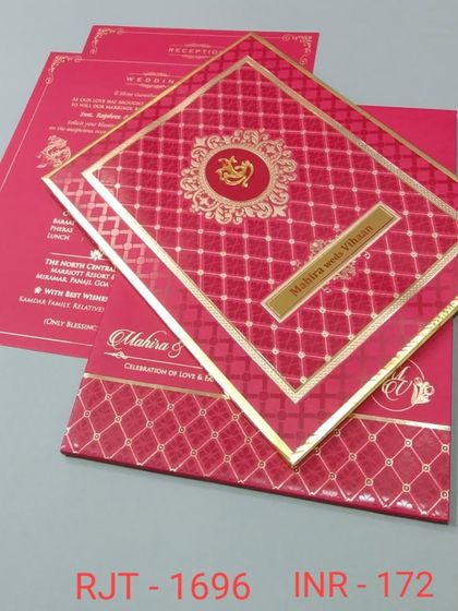 A vibrant red invitation with a central Ganesha motif, perfect for a traditional Hindu wedding. The card has a rich, textured feel and gold foil accents.
