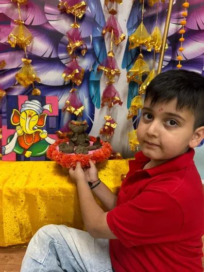 A young boy places his handmade Ganesha in a beautifully decorated home temple.