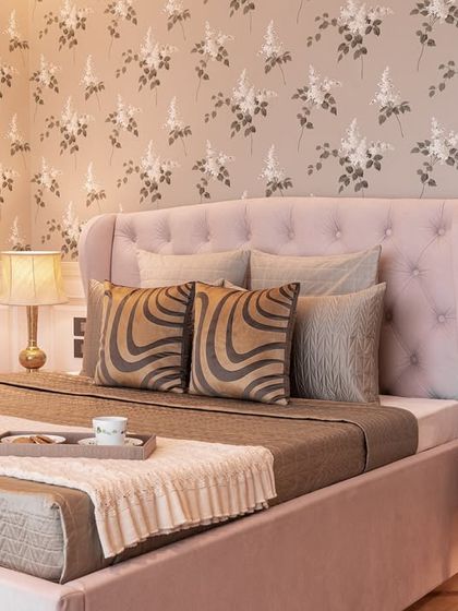 This bedroom is a beautiful blend of heritage and contemporary design, inspired by Parsi decor for the family's grandmother. The floral wallpaper and tufted pink bed create a space that feels both timeless and comfortable.