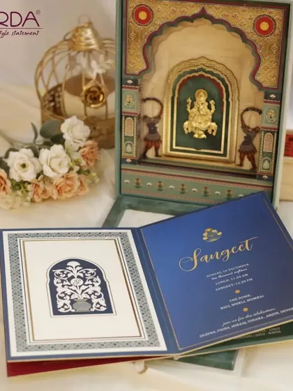 This Sangeet invitation box features a stunning 3D Ganesha idol within a golden temple structure. The accompanying invitation card in royal blue and gold sets a festive and luxurious tone for the musical celebration.