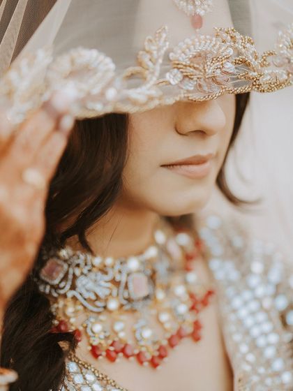 A close-up shot of the bride peeking from under her embroidered veil, a mysterious and beautiful portrait.