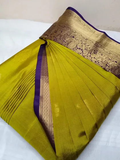 An olive green silk saree with a rich purple and gold border.