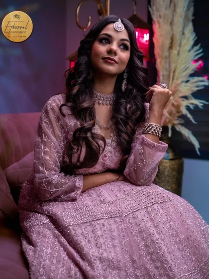 A relaxed, seated portrait that shows the full styling of the outfit and jewellery. The composition and lighting create a sophisticated look, perfect for a fashion or makeup lookbook.
