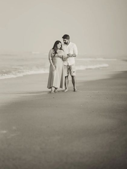 A full-length portrait of the couple standing by the waves. The black and white edit gives this beach pre-wedding photo a classic, elegant feel.