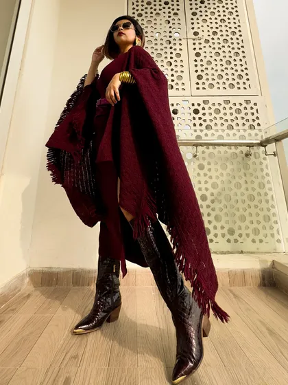 A full-length shot showing the entire silhouette, from the sunglasses to the pointed-toe boots.