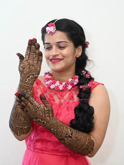 Celebrating love's intricate patterns. This bride is admiring her detailed henna, a beautiful and essential part of her wedding preparations.