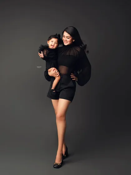 A full-length shot of a mother holding her smiling baby girl, both looking absolutely stunning.