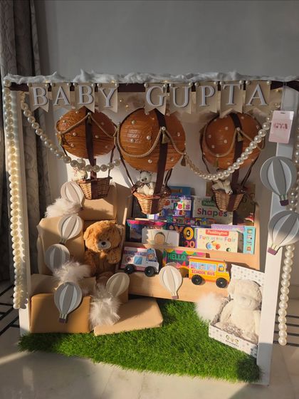 A full view of the hot air balloon themed bookshelf, showcasing the personalized banner, pearl garlands, and soft teddy bears.